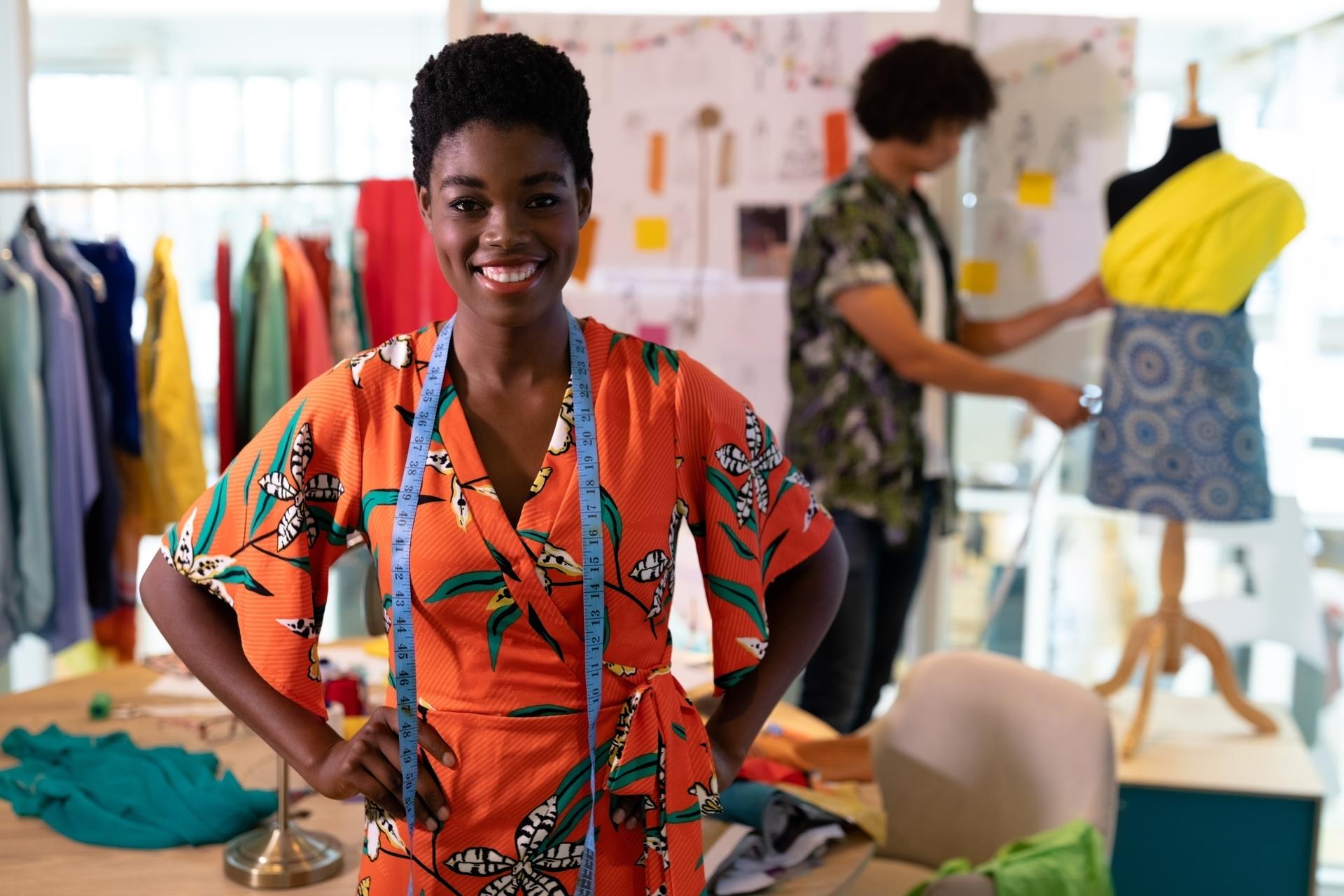 Female fashion designer standing with hands on hip in design studio