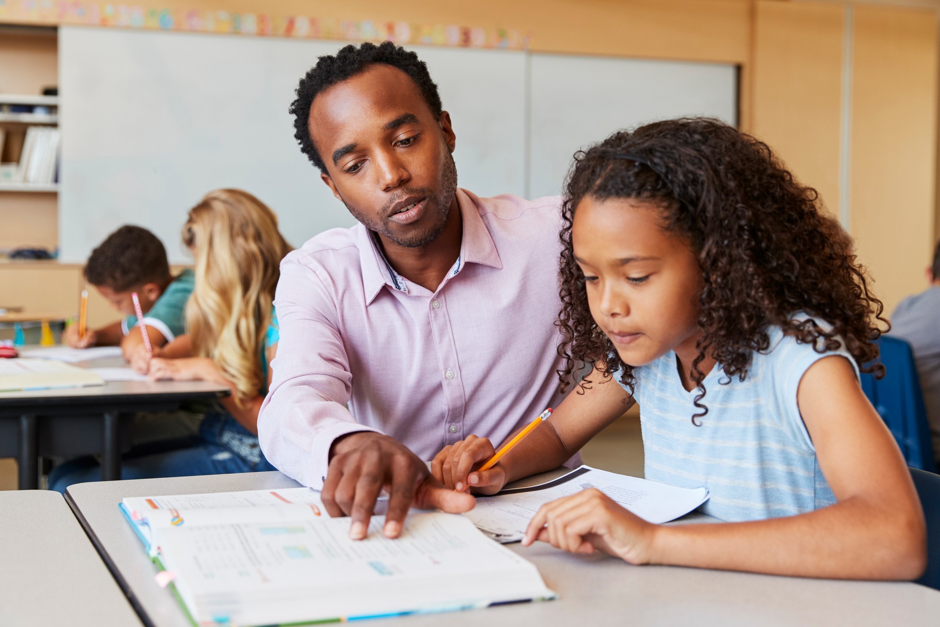 Teacher working with elementary school girl at her desk