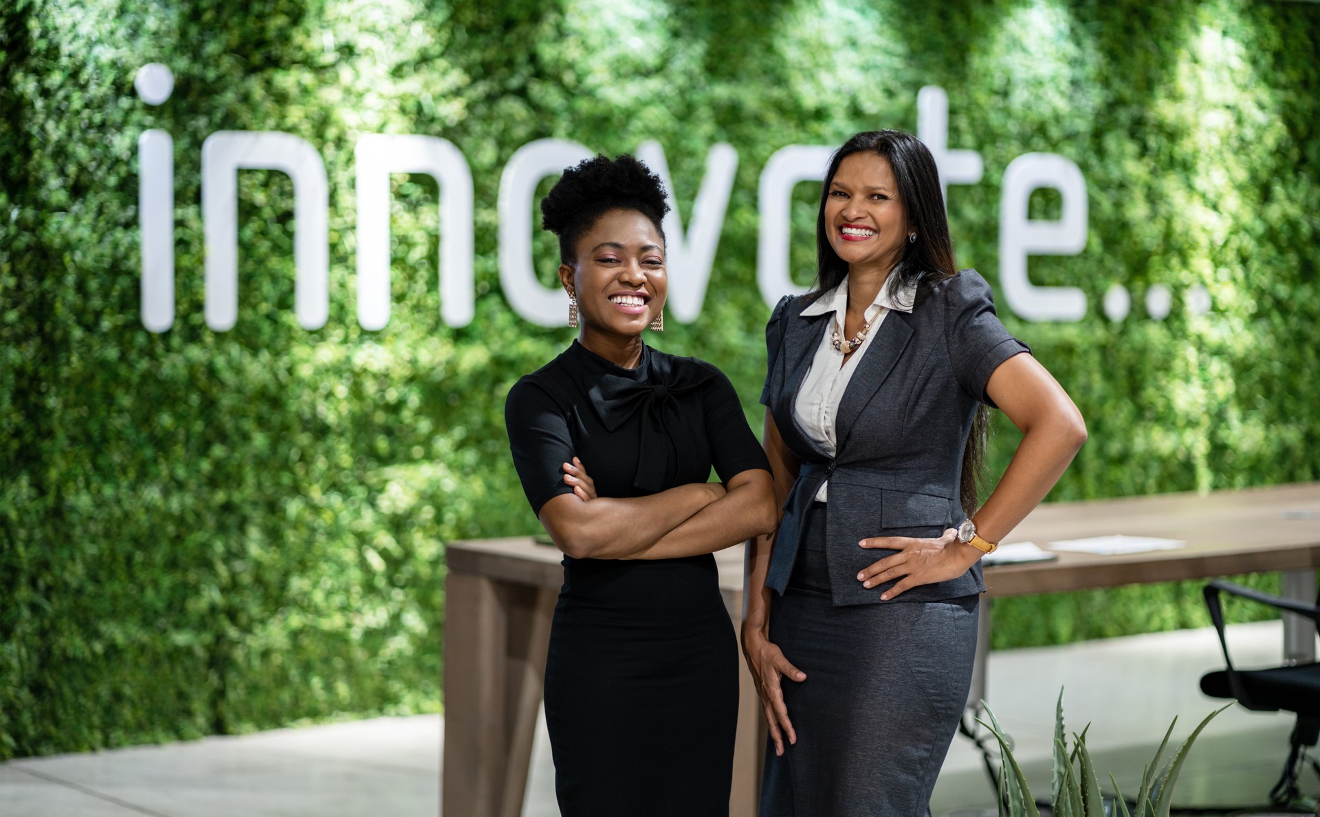 Portrait of a diverse young African business woman smiling while standing together in an eco-friendly modern office space